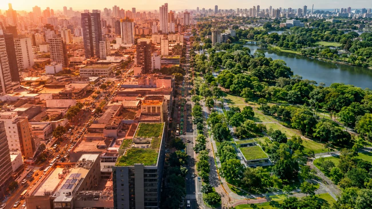 Vista aérea de uma cidade mostrando o contraste entre prédios densos com telhado verde e um parque arborizado ao lado